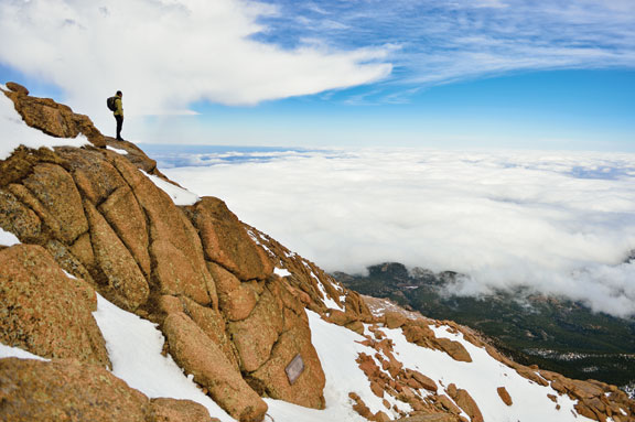 Man with a mountainsmith packs looks off of Pike's Peak above the clouds