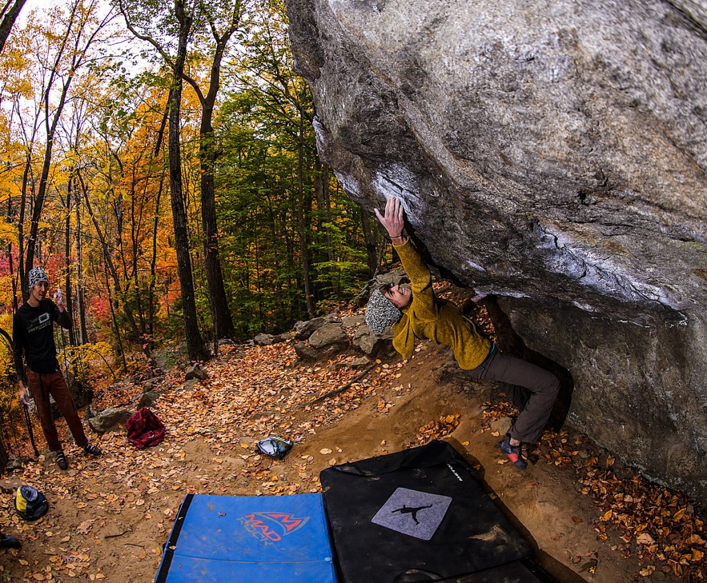 climber bouldering in Lincoln Woods, Rhode Island with a colorful autumn background