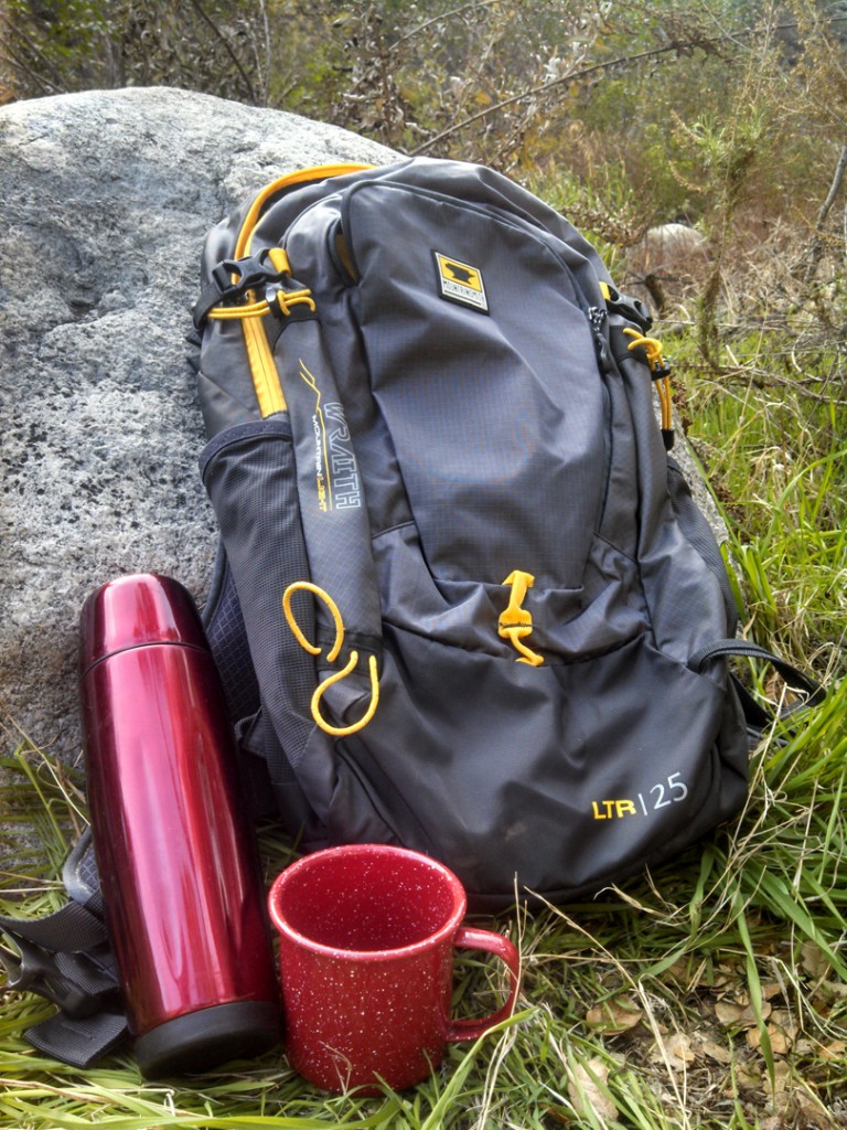 A coffee urn and mug next to the Mountainsmith Wraith 25 backpack