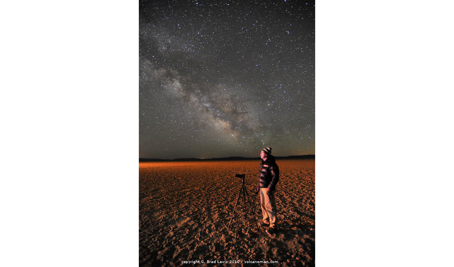 Grant Kaye, photographer, time lapse cinematographer, educator and Mountainsmith Ambassador pictured in the sand next to his tripod under a starry sky. 