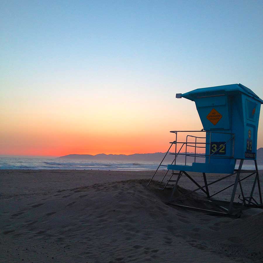 Sunset at Grover Beach, California. Blue lifeguard stand in the foreground, and a colorful sunset over the ocean in the background.