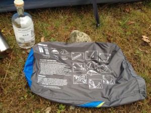The instructions of the Mountainsmith Genesee Tent appear on the side of the stuff sack next to a bottle of gin