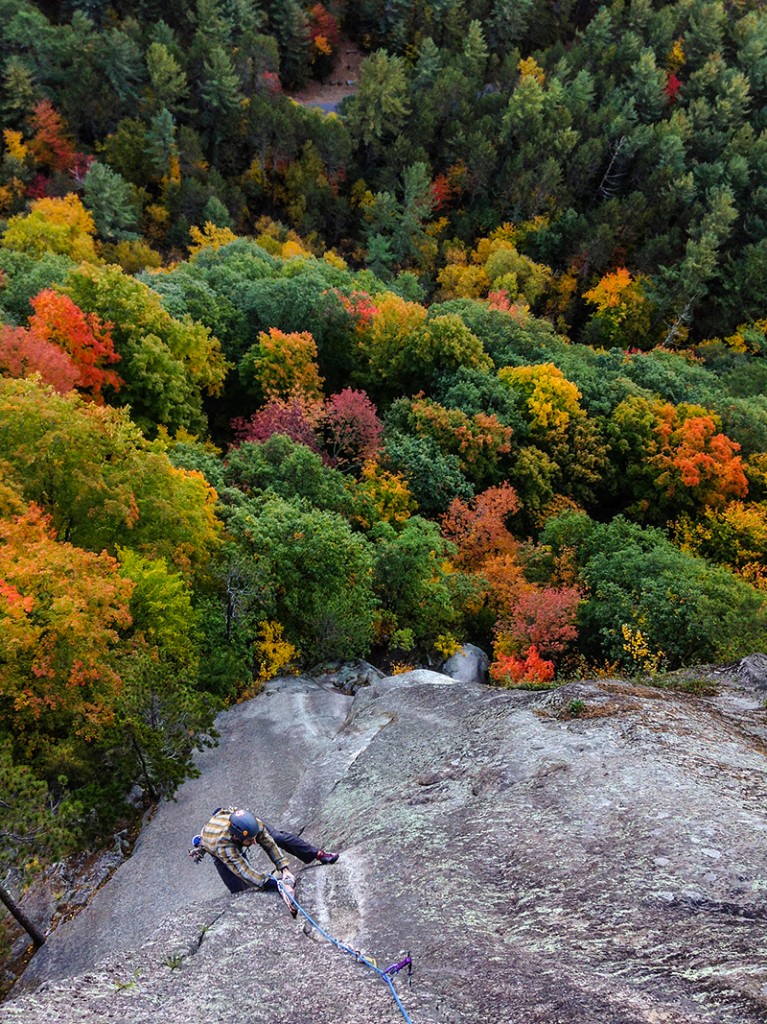 Climbing at Cathedral Ledge, New Hampshire with a colorful green and yellow background in the fall. 