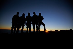 silhouettes of hikers standing at the summit of mt. kilimanjaro in tanzania