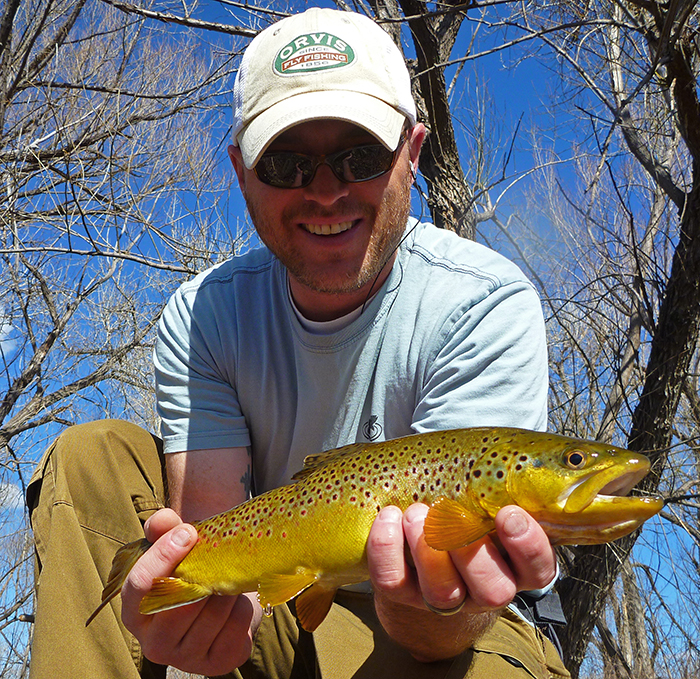 Jonathan Hill, writer, photographer and fly fisher and Mountainsmith Ambassador shown holding a trout while out fishing in Denver, Colorado