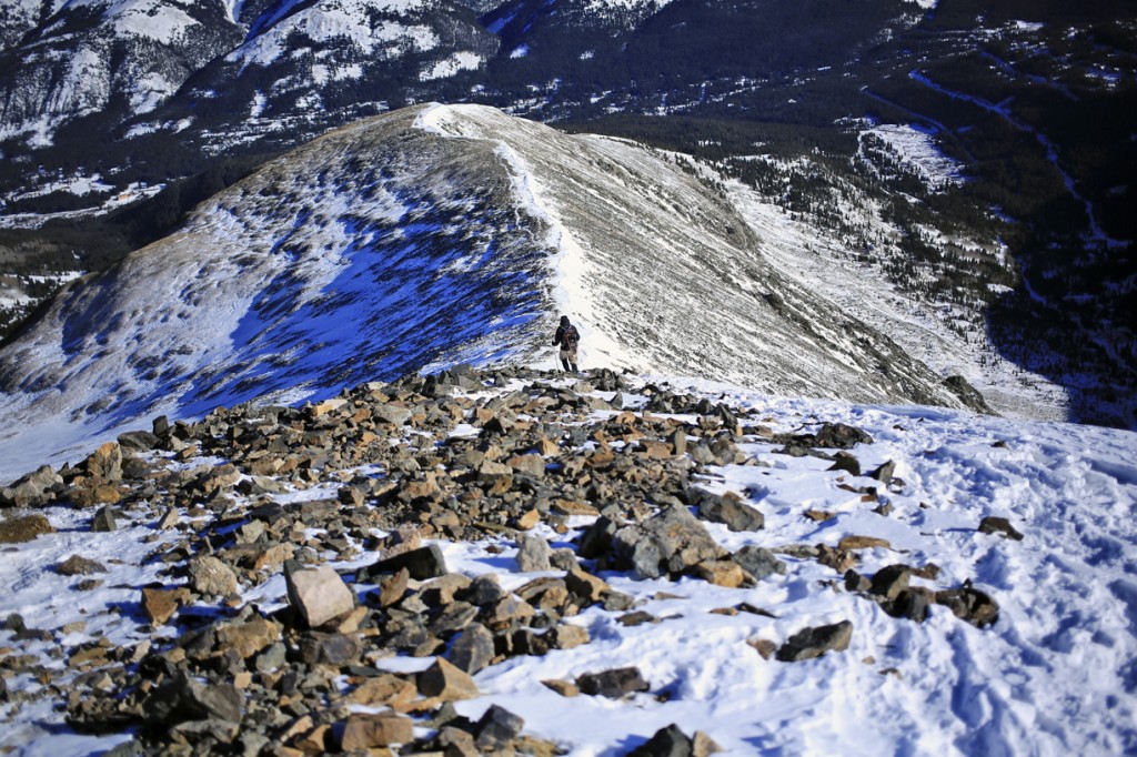 a hiker approaches the summit along the ridge line of Quandary Peak during winter in Colorado
