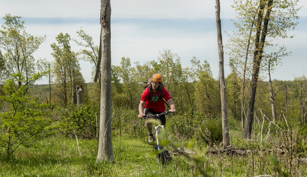 Curtis Savard riding a mountian bike through a cow pasture in Missouri, image by Aaron Codling