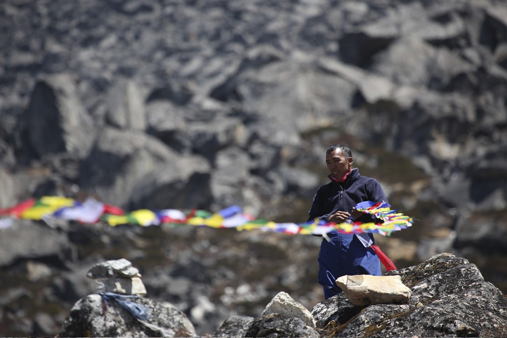A man holds prayer flags at a Puja ceremony at a Himalayan Basecamp.
