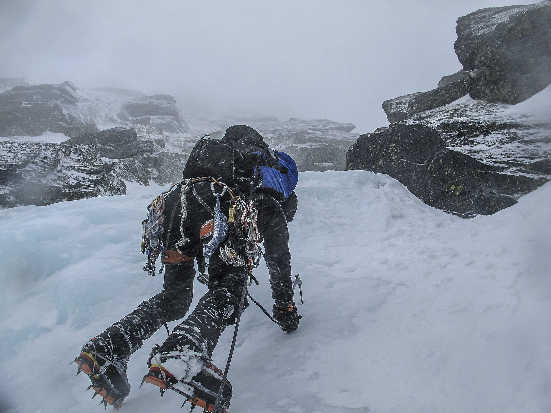 a mountaineer clings to ice with crampons and an ice ax, photo by Chris Vultaggio