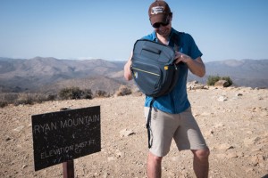 Man reaching into Mountainsmith camera bag while hiking