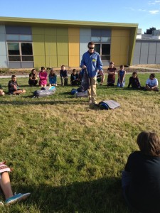 Jeremy Dodge presents to the Denver Green School students on the soccer field, setting up the Conifer 5+ tent