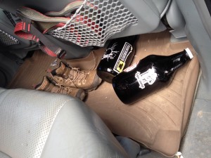 Two growlers, one from Cannonball Creek and one from Golden City Brewery with an UpaDowna sticker roll around the back seat of a car