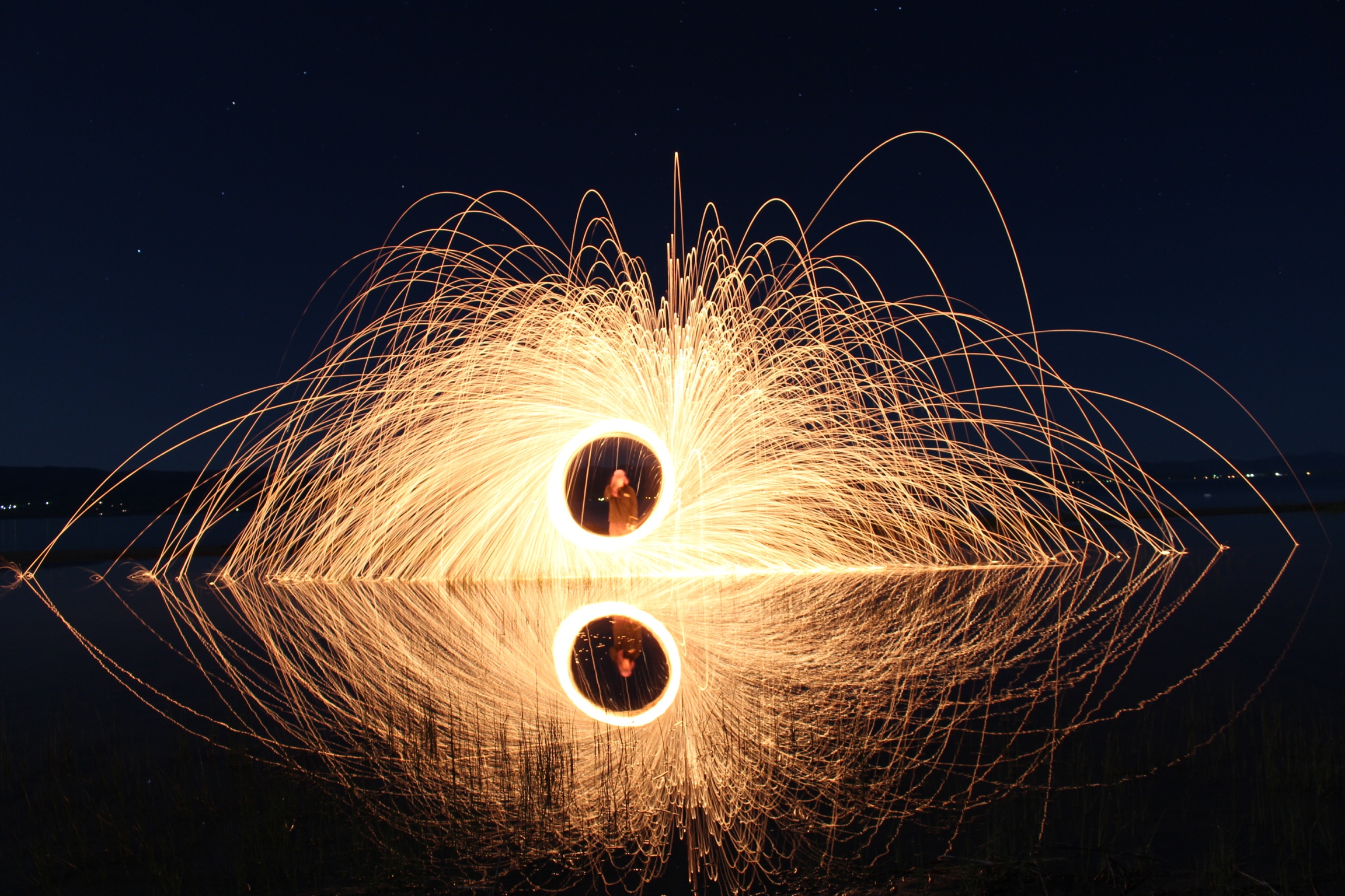 Andy Nichols creates a stunning night image by using a slow shutter speed and flaming steel wool that he lit on fire and spun around in circles over a lake. 